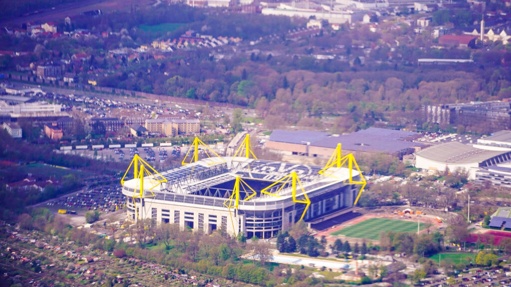 Der Signal Iduna Park ist das Zuhause von Borussia Dortmund BVB und eines der bekanntesten Fußballstadien der Welt. Mit einer Kapazität von über 81.000 Zuschauern bietet das Stadion eine einzigartige Atmosphäre und Stimmung bei jedem Spiel. Fussball Stadion ehemals Westfalen Stadion. Das Luftbild zeigt auch die Umgebung des Stadions, einschließlich der grünen Landschaft und der umliegenden Gebäude.